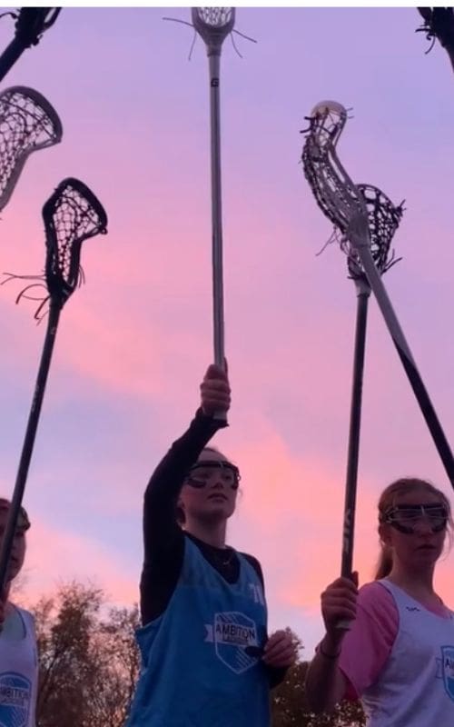A group of people holding lacrosse sticks in the air.