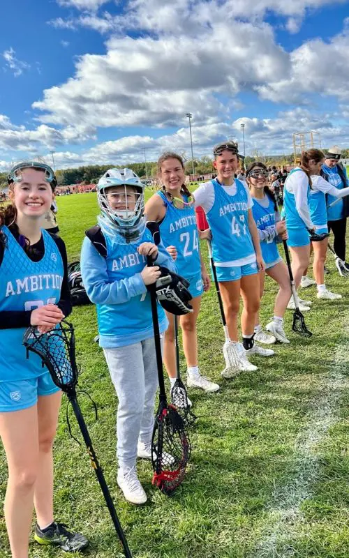 A group of girls in blue uniforms holding lacrosse sticks.