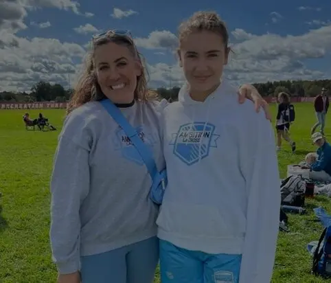 Two women standing next to each other in a field.