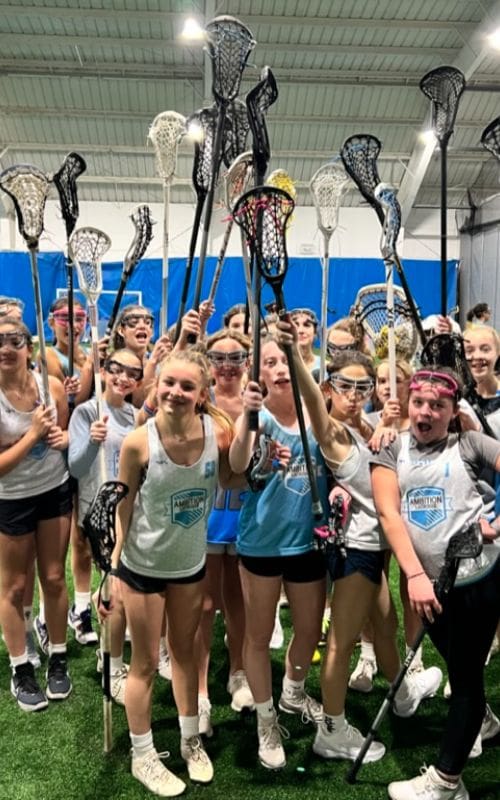 A group of girls holding lacrosse sticks in the air.