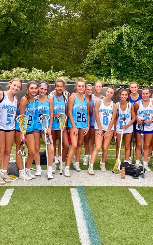 A group of girls standing next to each other holding lacrosse sticks.