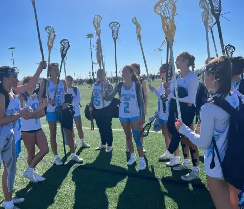 A group of girls holding lacrosse sticks on top of a field.