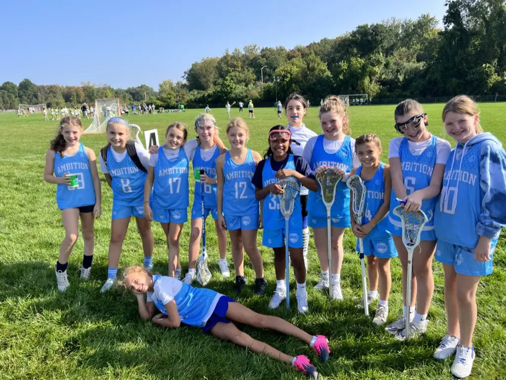 A group of girls in blue jerseys holding lacrosse sticks.