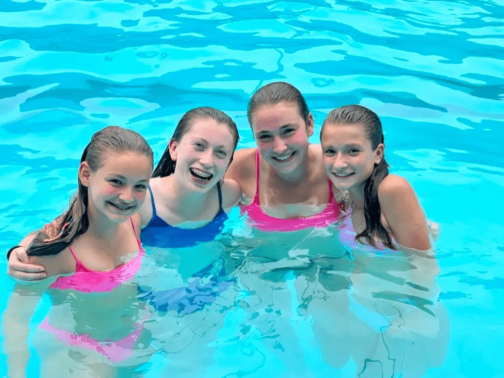 A group of girls in the water smiling for the camera.