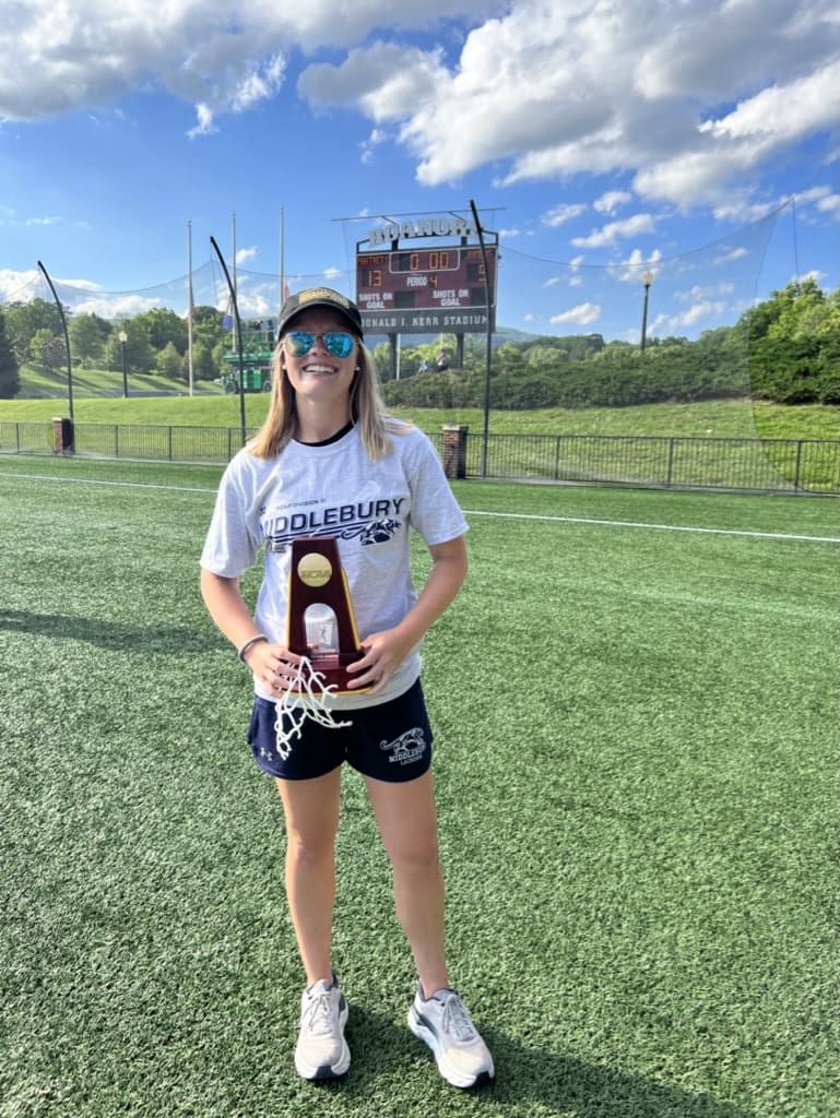 Woman holding Middlebury lacrosse trophy.